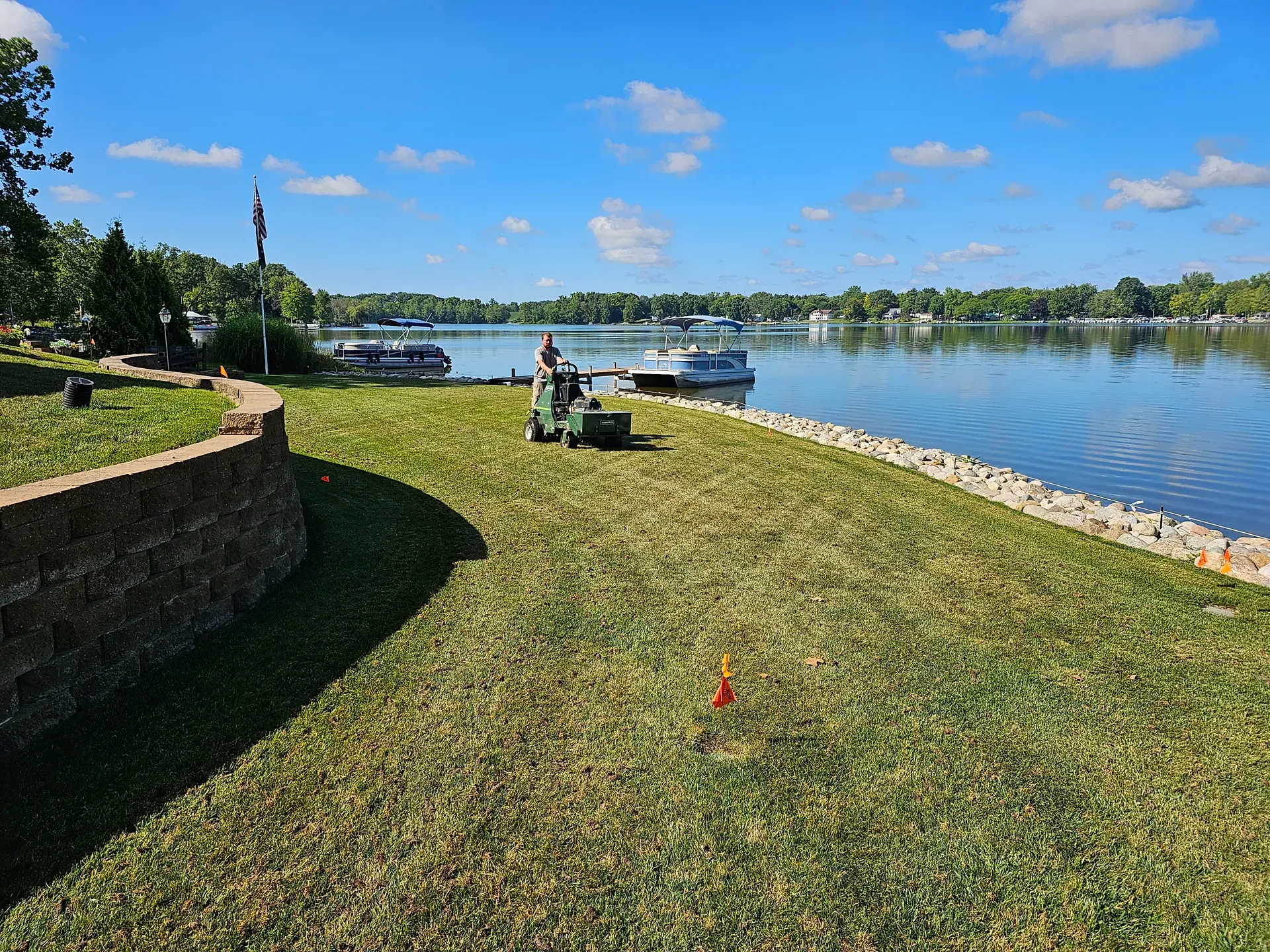 An aerated lawn beside the water with soil cores scattered across the turf