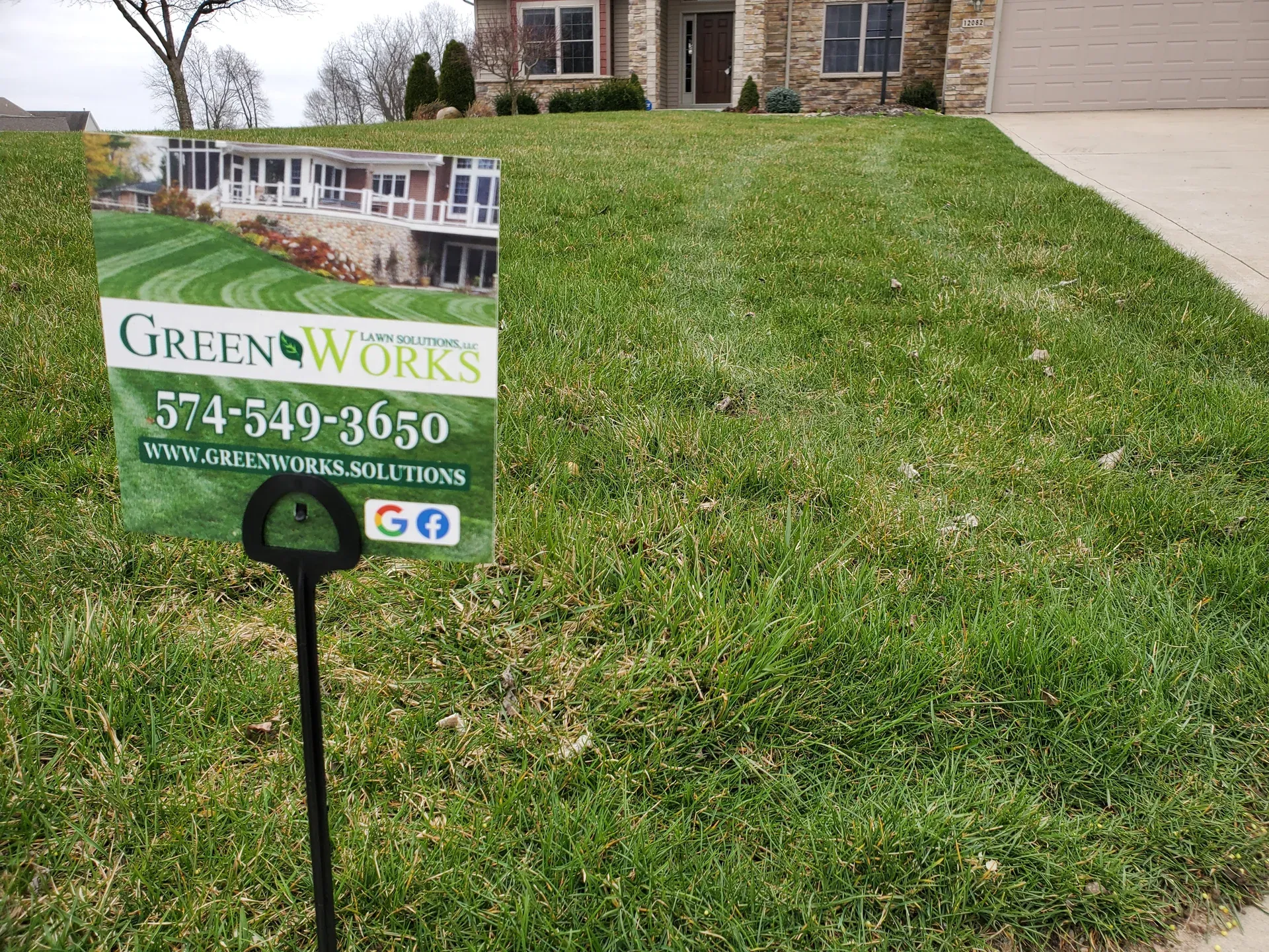 A GreenWorks yard sign standing in a treated front lawn