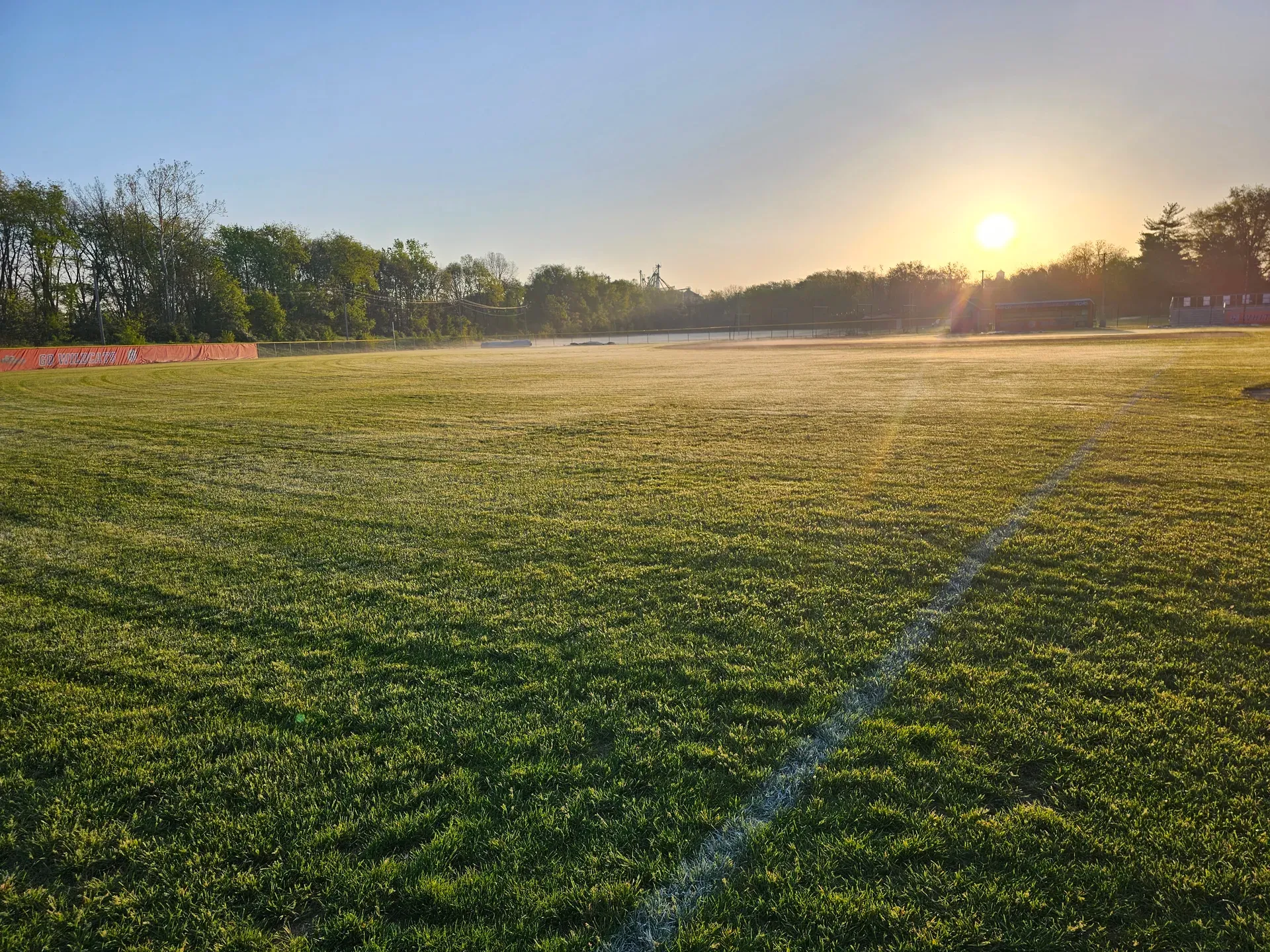 An athletic field at sunrise with dense, evenly treated turf